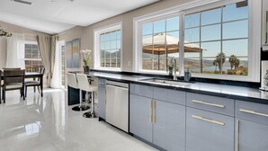 A modern kitchen with large windows, a dining area, and a view of the outdoors. - Luxury 4 BR w/ Serene Lake Views (Spring Valley)