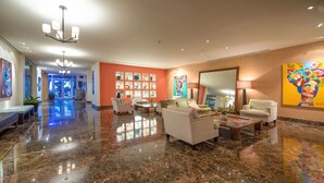 A spacious lobby with a polished marble floor, seating areas, and artwork on the walls.