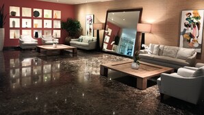A modern lobby with a marble floor, two sofas, a coffee table, and a large mirror.