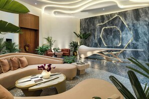 A modern interior with a curved sofa, a coffee table, and a unique wall design. - UNFRAMED, Autograph Collection (Miami Beach)