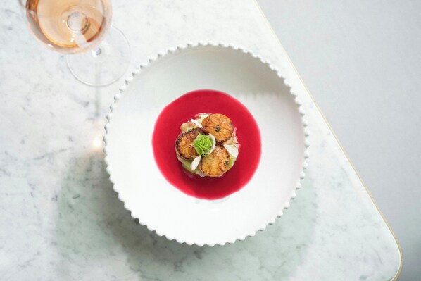 Un plato blanco con salsa roja y un alimento sobre una superficie de mármol.
