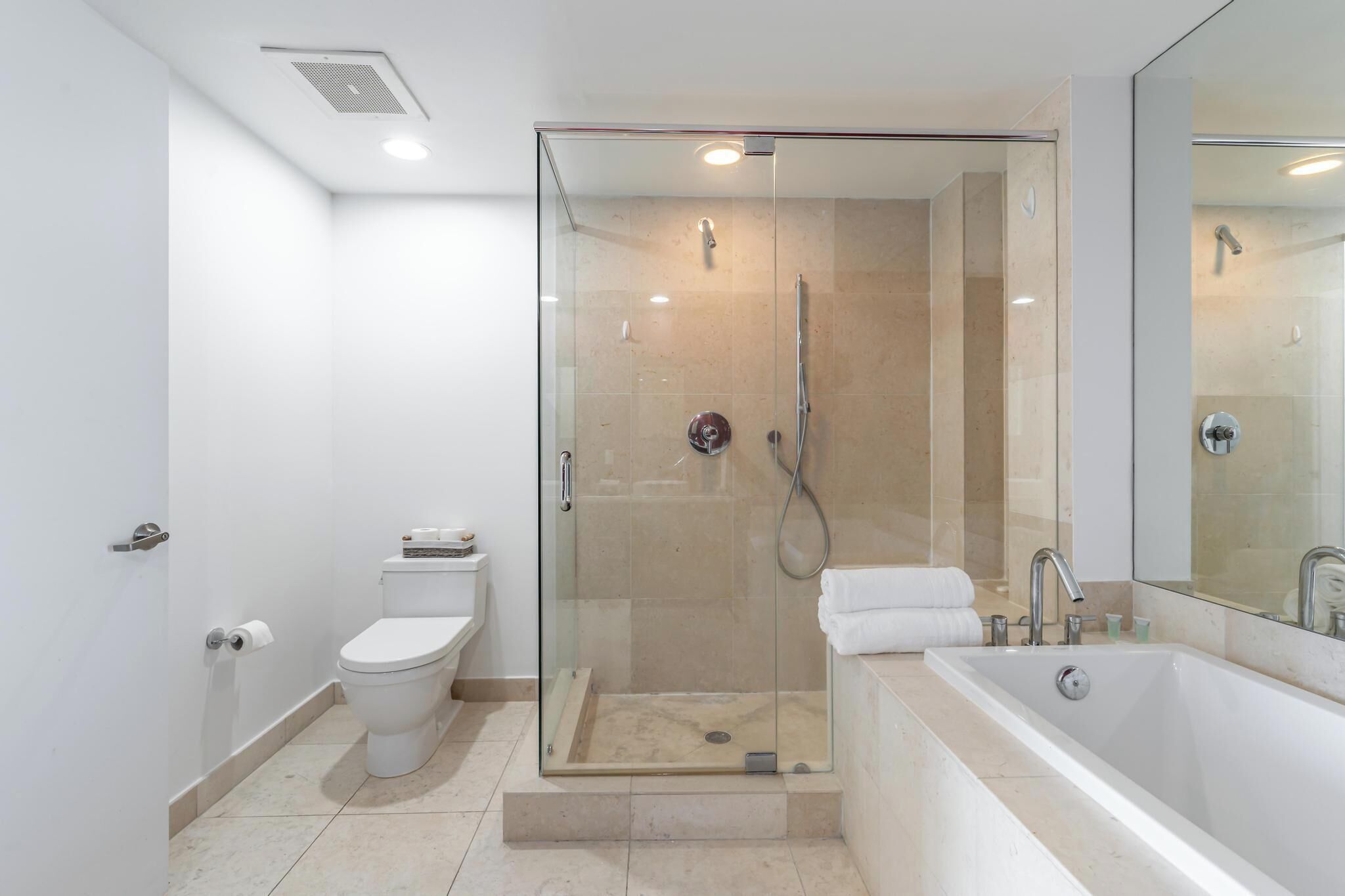 A modern bathroom with a glass-enclosed shower, a white toilet, and a large bathtub.