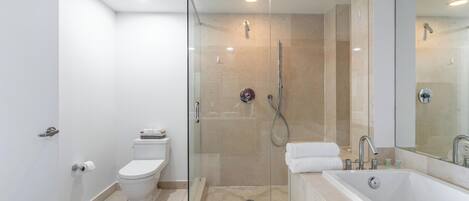 A modern bathroom with a glass-enclosed shower, a white toilet, and a large bathtub.