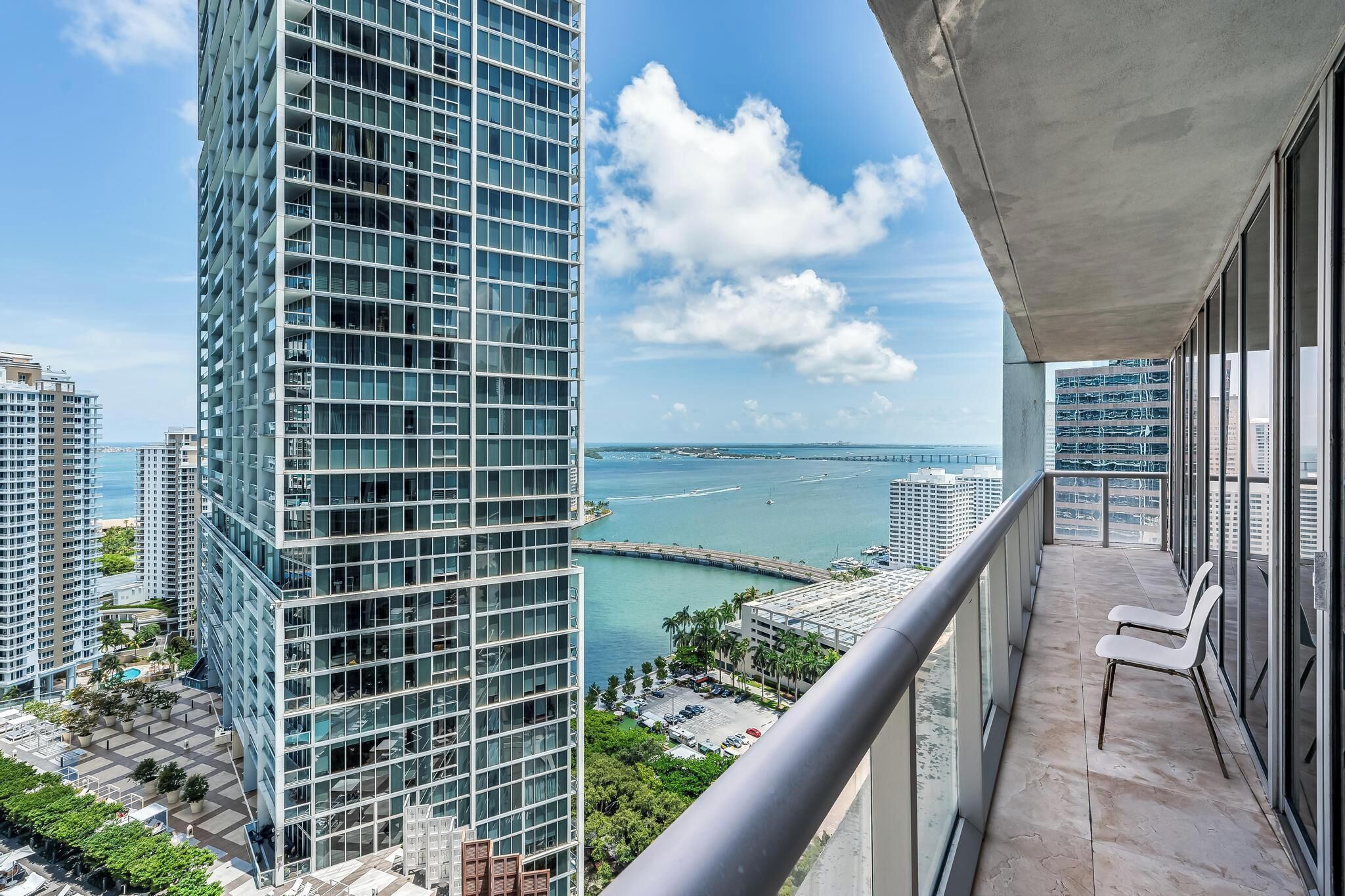 A high-rise building with a balcony overlooking a marina and cityscape.