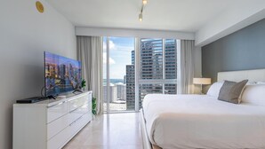A modern hotel room with a large bed, a flat-screen TV, a city view, and a balcony. - ICON Brickell Miami- 2 bedroom Condo with City and water views! (Miami)
