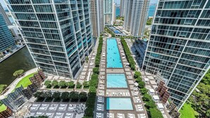 A high-rise building with a central swimming pool surrounded by lounge areas and greenery. - ICON Brickell Miami- 2 bedroom Condo with City and water views! (Miami)