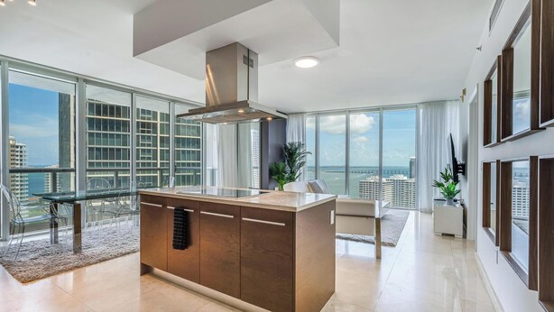 A modern kitchen with a large island, large windows, and a view of the city. - ICON Brickell Miami- 2 bedroom Condo with City and water views! (Miami)