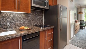 Una cocina moderna con encimeras de granito, electrodomésticos de acero inoxidable y armarios de madera.