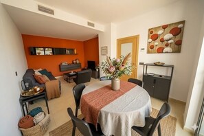 A compact living space with a dining area, a sofa, a coffee table, and a decorative vase.