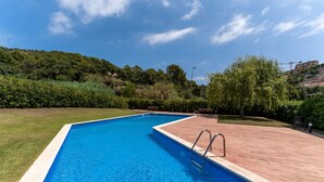 Ein rechteckiger Pool mit klarem, blau schimmerndem Wasser, umgeben von einer Ziegelterrasse und üppiger Vegetation.