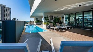 Un espace piscine aménagé sur le toit, avec des chaises longues et une vue sur le paysage urbain.