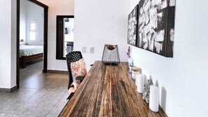 Een moderne eetruimte met een houten tafel, stoelen en een groot abstract schilderij aan de muur.