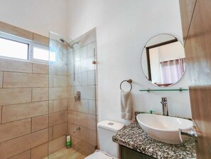 Une salle de bain équipée d’une douche, de toilettes, d’un lavabo et d’un miroir.