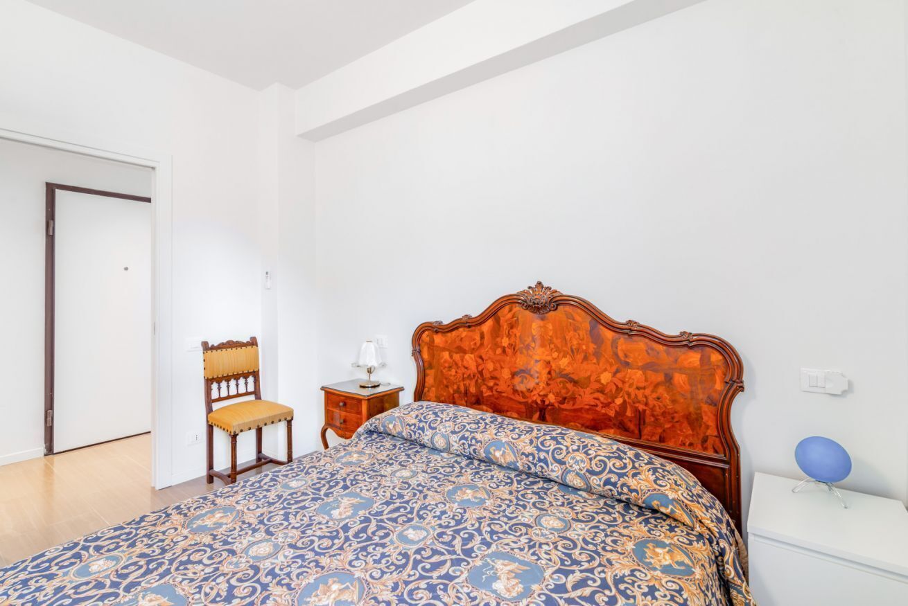 A bedroom with a wooden bed, a chair, a bedside table, and a nightstand.