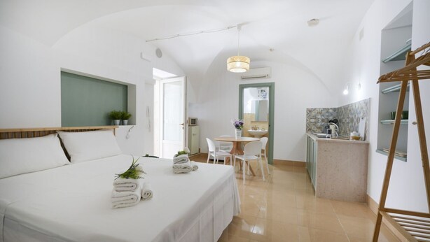 Una habitación de hotel con cama, una pequeña zona de comedor, kitchenette y baño.
