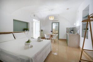 Una habitación de hotel con cama, una pequeña zona de comedor, kitchenette y baño.