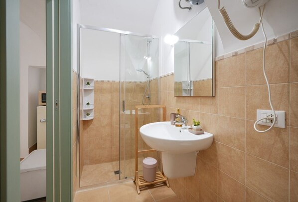 Un baño con ducha envuelta en vidrio, un lavabo con espejo y un perchero para toallas.