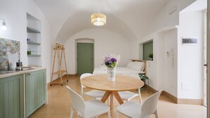 Una cocina moderna con armarios blancos, una mesa redonda de madera y sillas blancas.