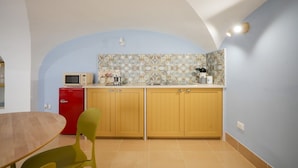 Una cocina compacta con microondas, lavamanos y armarios.