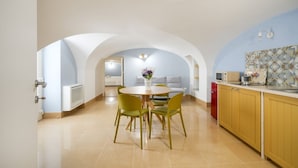 Una cocina moderna con armarios amarillos, un comedor con una mesa redonda y sillas, y una sala de estar con un sofá y un jarrón decorativo.