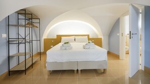 A bedroom with a bed, a wooden shelf, and a door leading to another room.