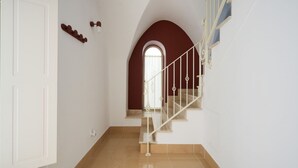 A staircase with a white railing, a red archway, and a white door.