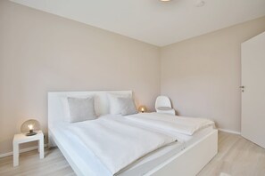 Un dormitorio minimalista con cama, mesita de noche y silla.