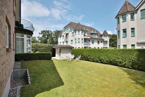 Un immeuble résidentiel doté d’une pelouse bien entretenue et d’un petit patio aménagé avec du mobilier d’extérieur.