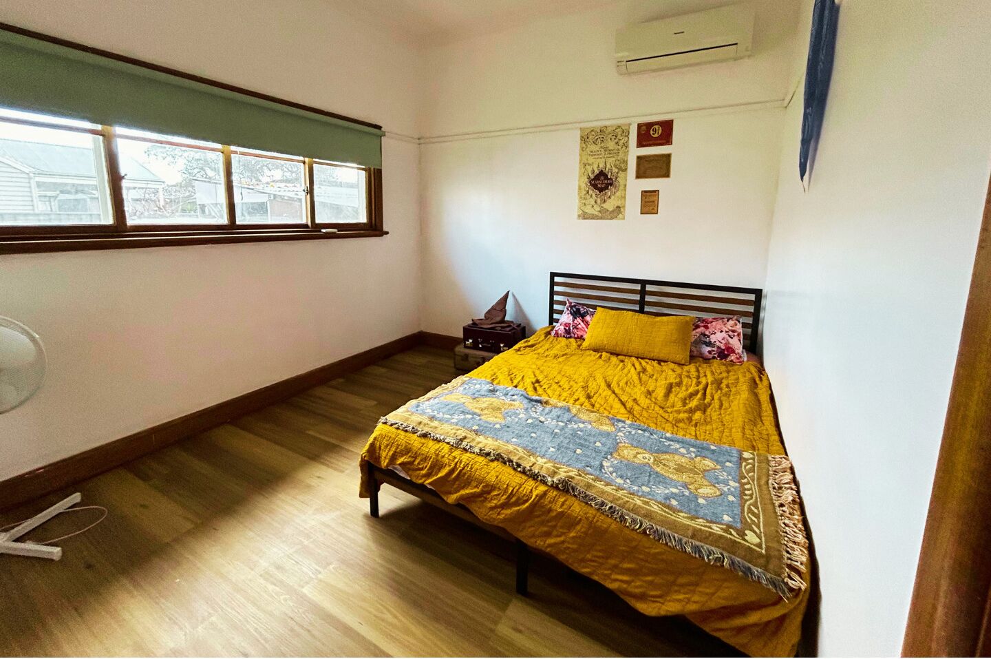 A bedroom with a bed, a nightstand, a window, and wall decorations.