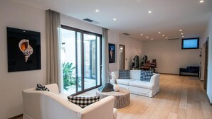 Una sala de estar moderna con un sofá blanco, una mesa redonda de centro y un ventanal con cortinas.