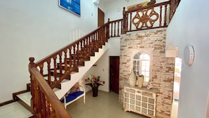 Una escalera con balaustres de madera que lleva a un rellano con un banco y un jarrón de flores.