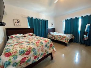A room with two beds, teal curtains, and a standing mirror. - Villa Niviades, Cumayasa, República Dominicana. Ideal Para Disfrute, Descanso! (La Romana)