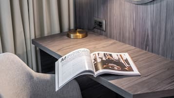 Una habitación moderna con un escritorio de madera, una lámpara y una revista abierta sobre el escritorio.