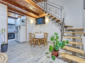 Staircase leads to an upper level, with a dining area and kitchen in view.