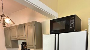 A kitchen with a white refrigerator, a stove, and a microwave on top of the fridge.