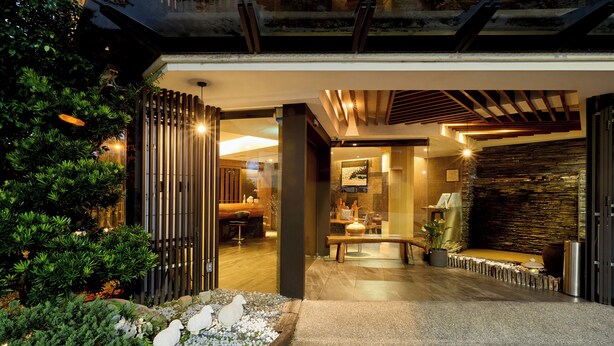 A modern interior with a stone wall, wooden ceiling, and a seating area with a bench and table. - Tenlien onsen Hot Spring Hotel (Jiaoxi)