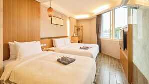 A hotel room with two beds, a TV, a wooden headboard, a window with curtains, and a hanging light fixture. - Tenlien onsen Hot Spring Hotel (Jiaoxi)