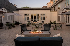 A patio with outdoor seating, a fire pit, and a building with large windows and doors. - Brookmere Saratoga, a Tribute Portfolio Hotel  (Saratoga Springs)