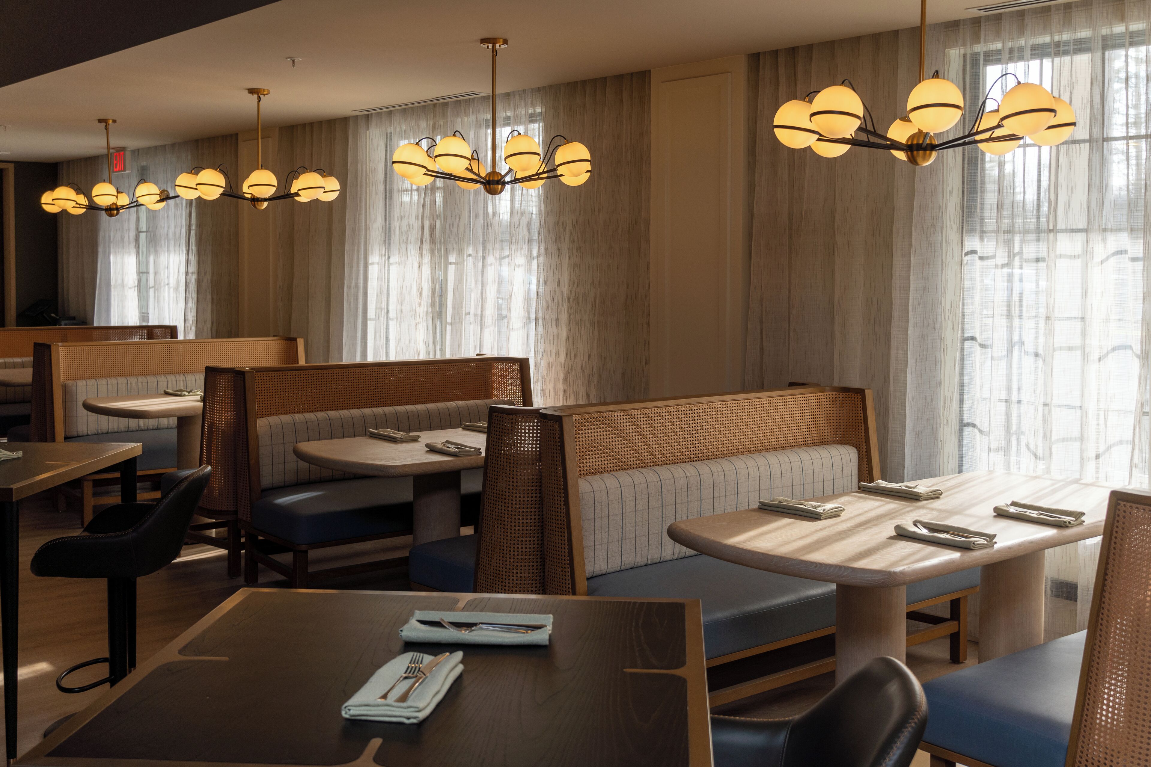 A restaurant with booths and tables, wooden furniture, and hanging light fixtures.