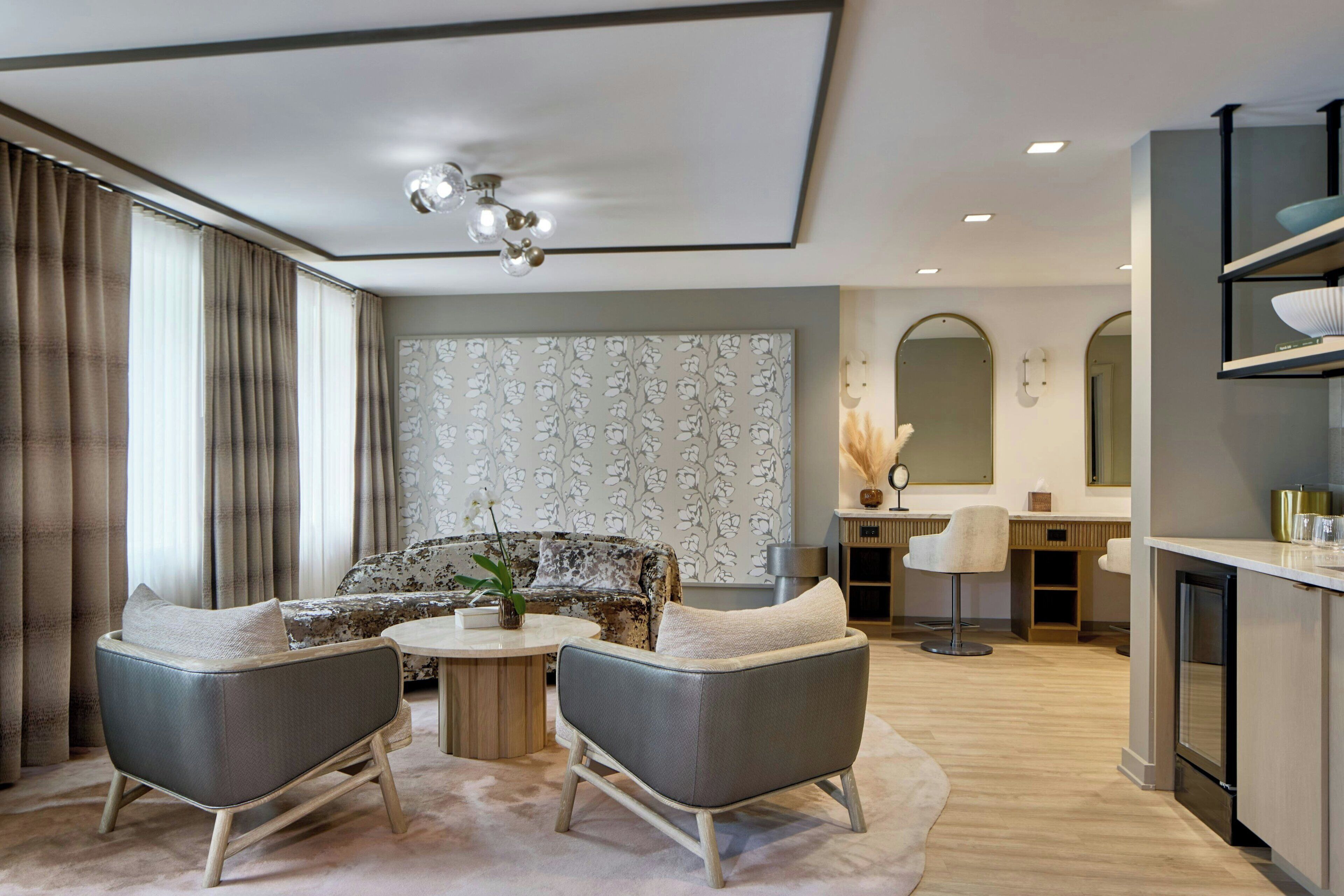 A modern living room with a sofa, two armchairs, a coffee table, and a dining area with a kitchen counter.