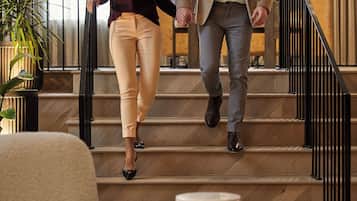 A man and a woman walking down a staircase in a hotel lobby with a modern interior design, including a potted plant and a round table.