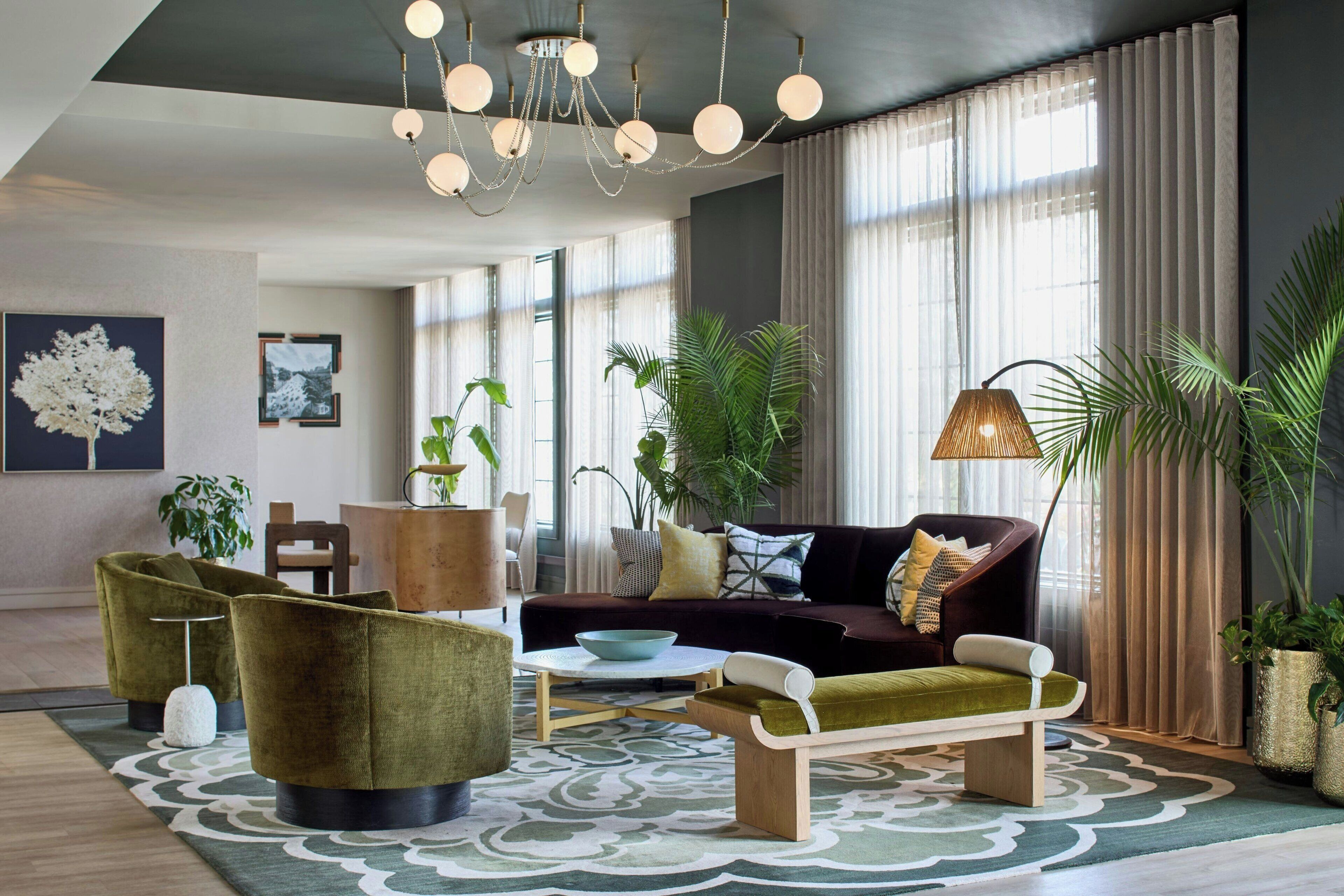Un salon moderne avec un canapé, des fauteuils, une table basse et un lustre.