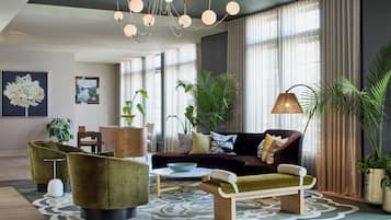 Un salon moderne avec un canapé, des fauteuils, une table basse et un lustre.