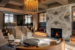 A spacious living area with a fireplace, modern furniture, and a staircase leading to an upper level. - Brookmere Saratoga, a Tribute Portfolio Hotel  (Saratoga Springs)