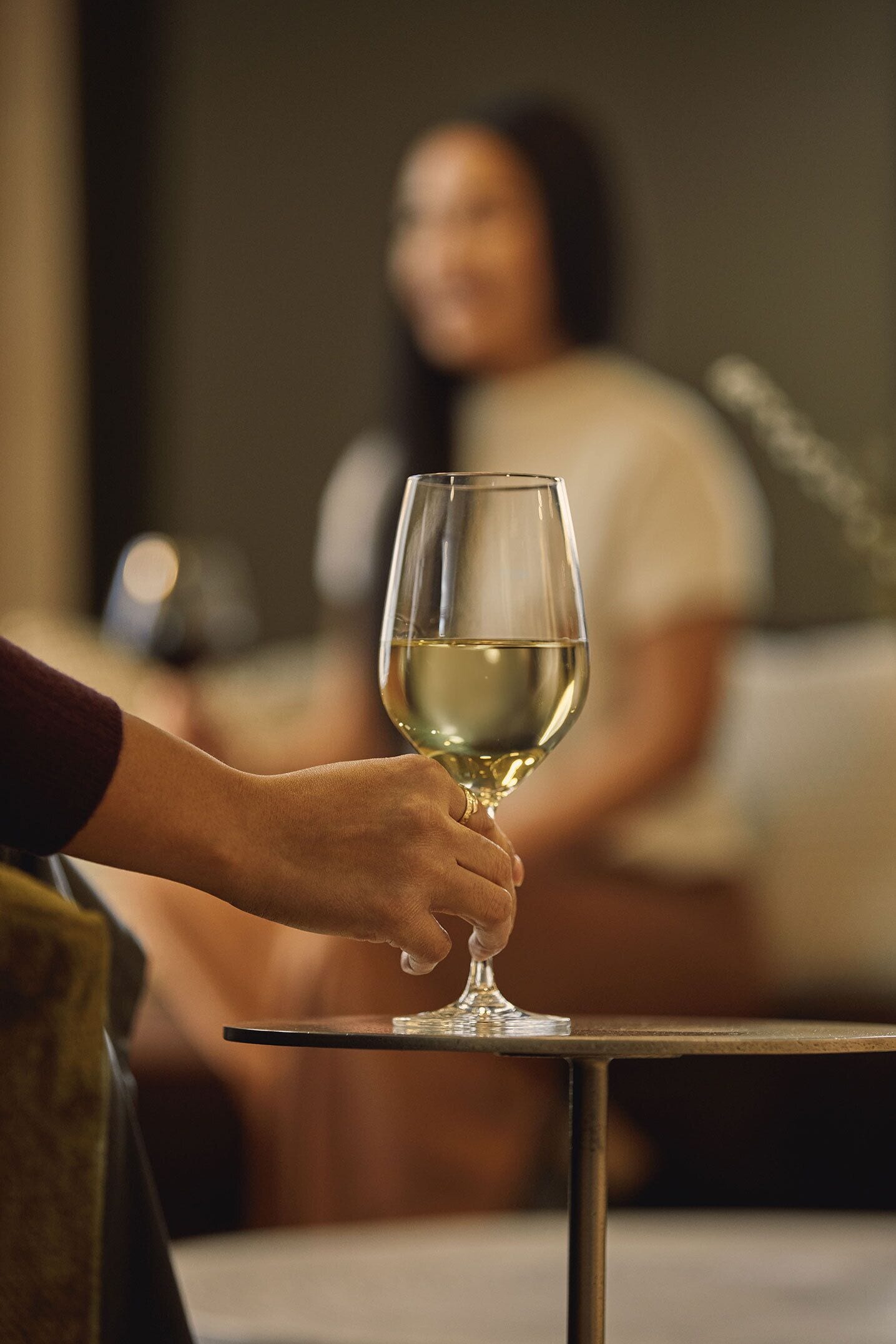 A person holding a wine glass on a table.