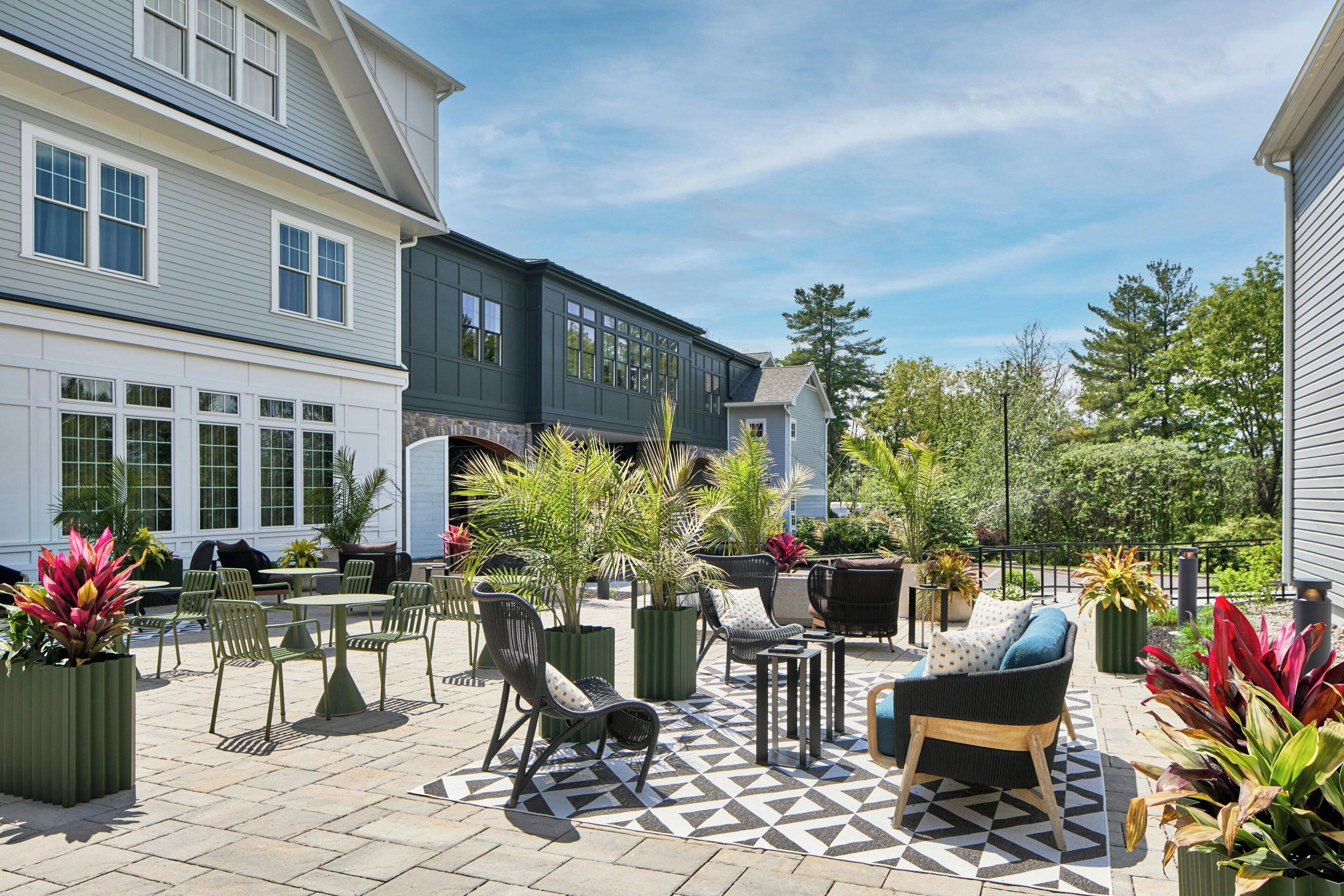 Un espace patio aménagé avec du mobilier d’extérieur, des plantes en pot et un sol à motifs.