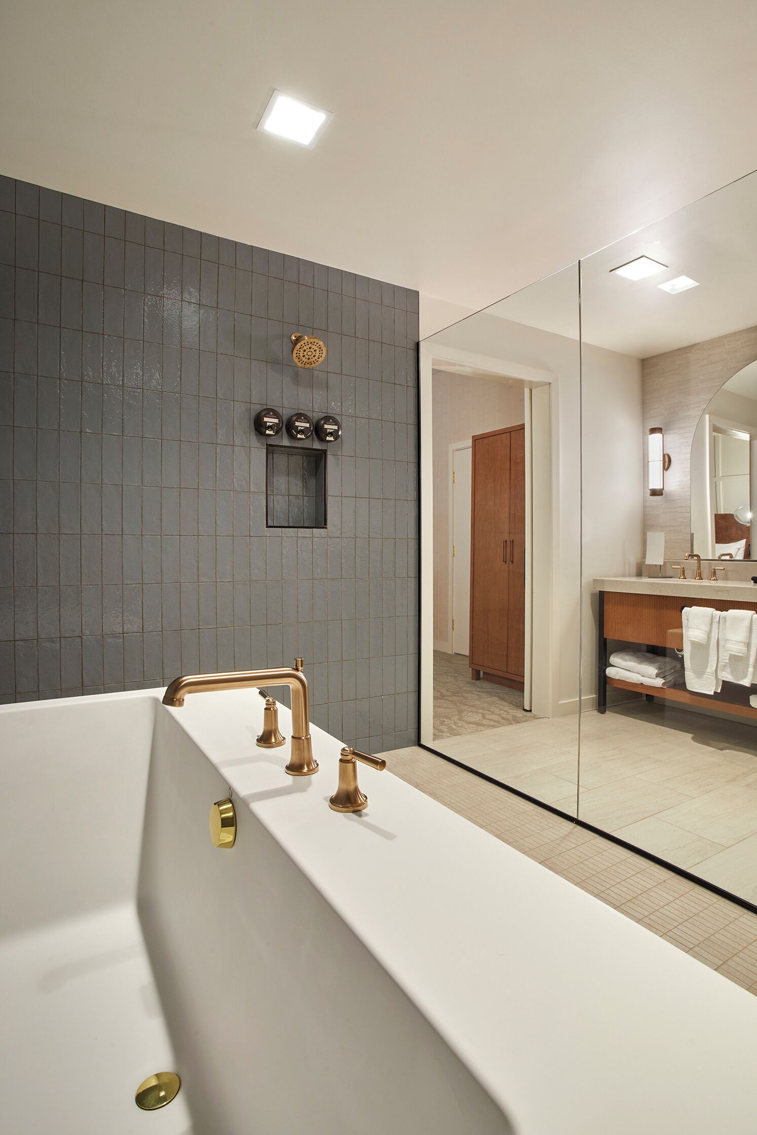 Un baño moderno con una bañera grande, un espejo y un tocador de madera.