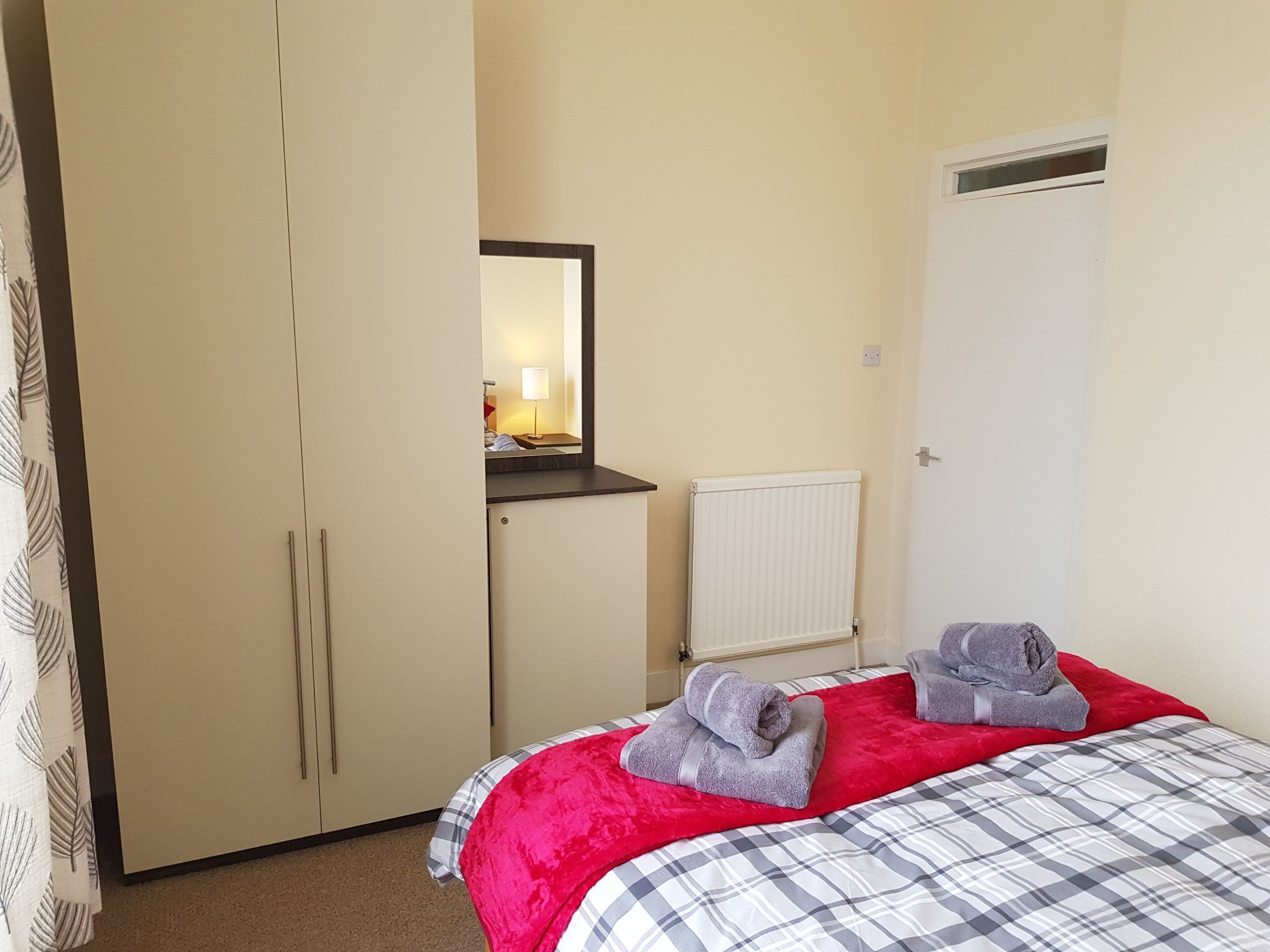 Une chambre à coucher avec un lit, une armoire, un radiateur et un miroir.