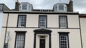 A two-story building with a central entrance, a parking sign, and a parking meter on the sidewalk. - Charlotte Street (Ayr)