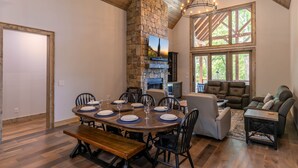A dining area with a stone fireplace, a large window, and a cozy seating area with leather sofas. - On Mountain Time at Eagles Nest - single level w/hot tub, views, firepit (Banner Elk)